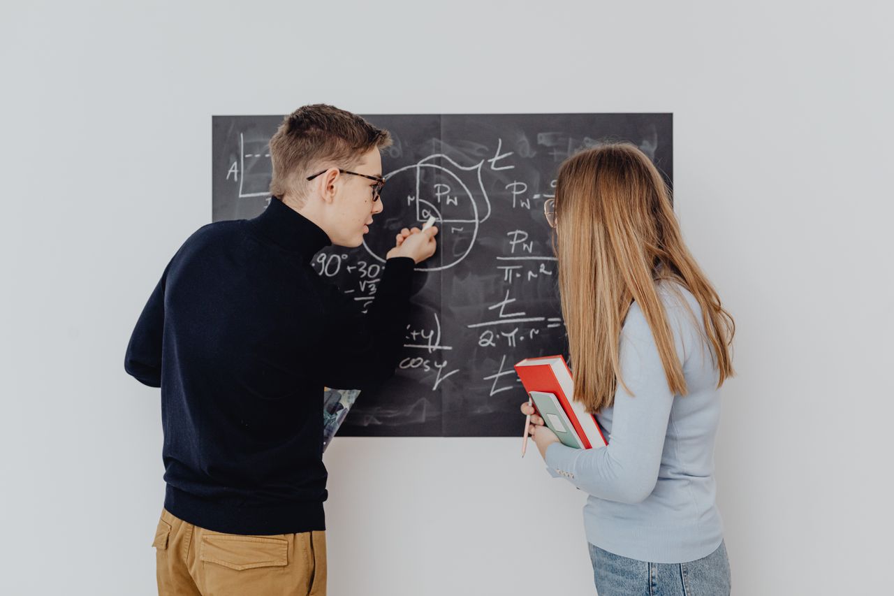 about-01 Two students working together on trigonometric equations on a blackboard, enhancing learning.