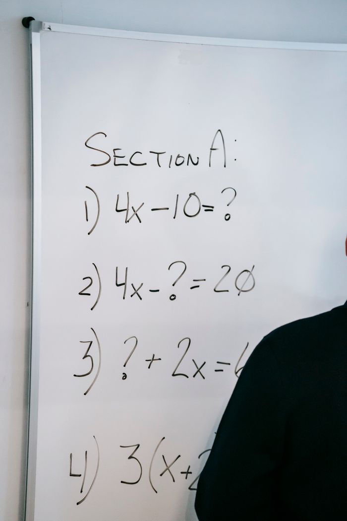 gallery-5 A whiteboard displaying math equations and partial silhouette of a person writing.